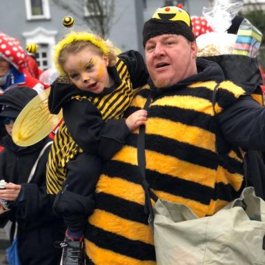 Ein Erwachsener und ein Kind in Bienenkostümen auf einer festlichen Veranstaltung.